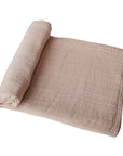 mushie organic cotton muslin swaddle blanket for baby in pale taupe