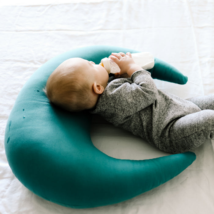 baby drinking milk with milk bottle on snuggle me organic feeding support pillow